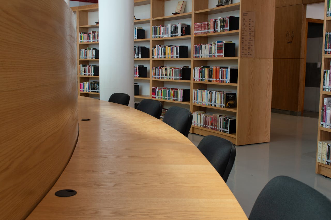 Spacious library interior featuring wooden bookshelves and a large conference table.