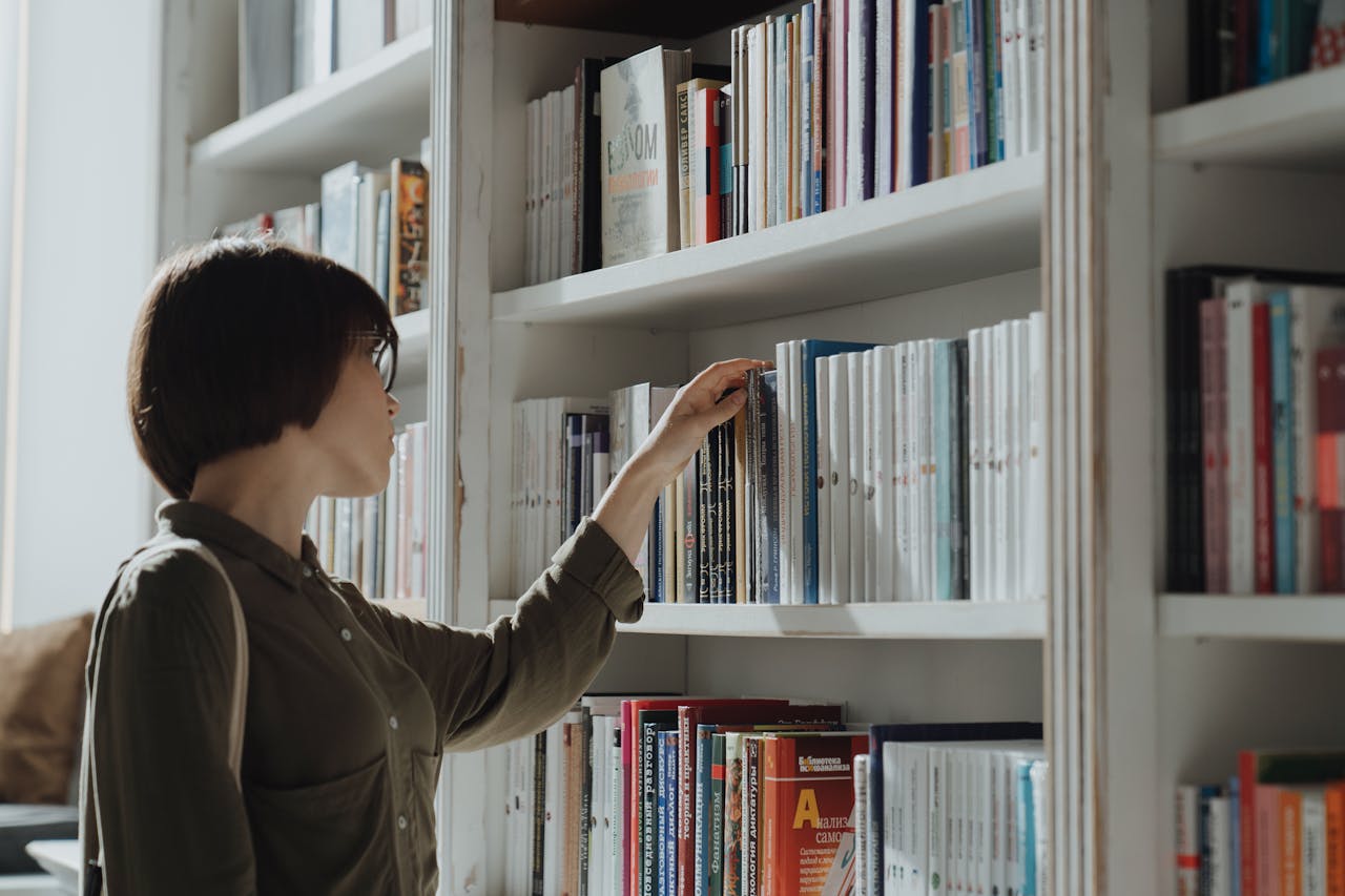 A woman browsing a bookshelf in a modern library setting, exploring various literature options.